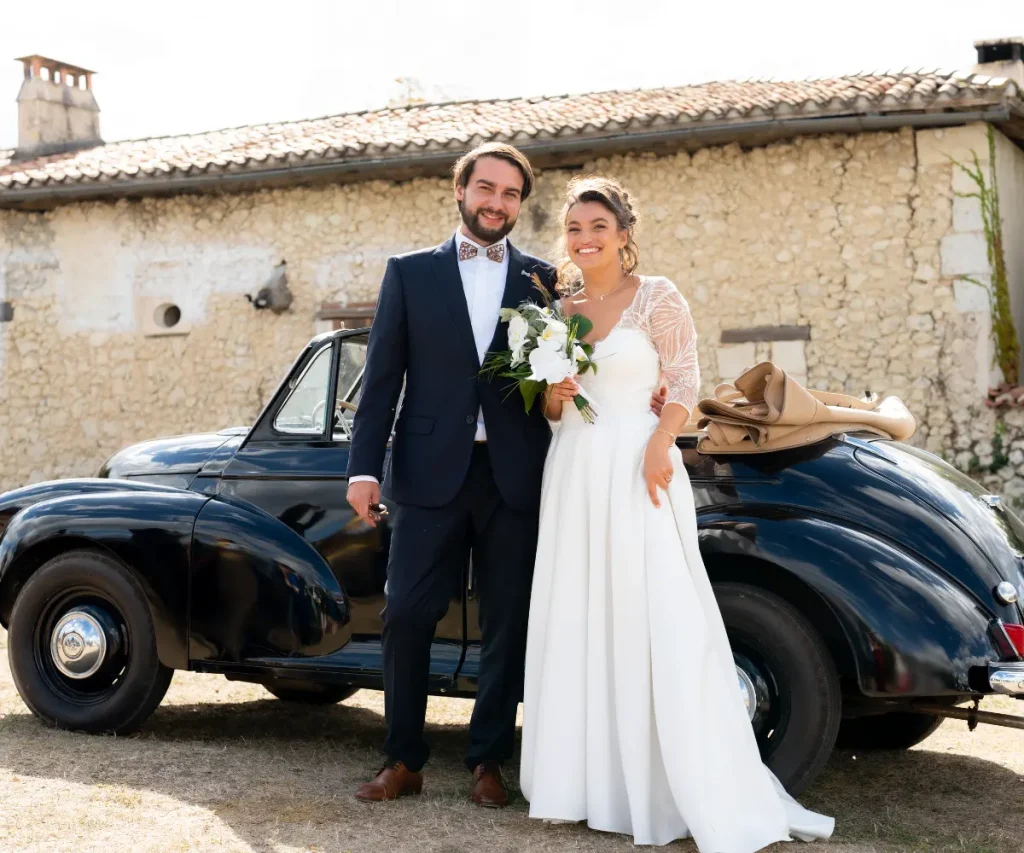 Couple de jeunes mariés devant une voiture vintage en Dordogne, mariage élégant organisé par wedding planner