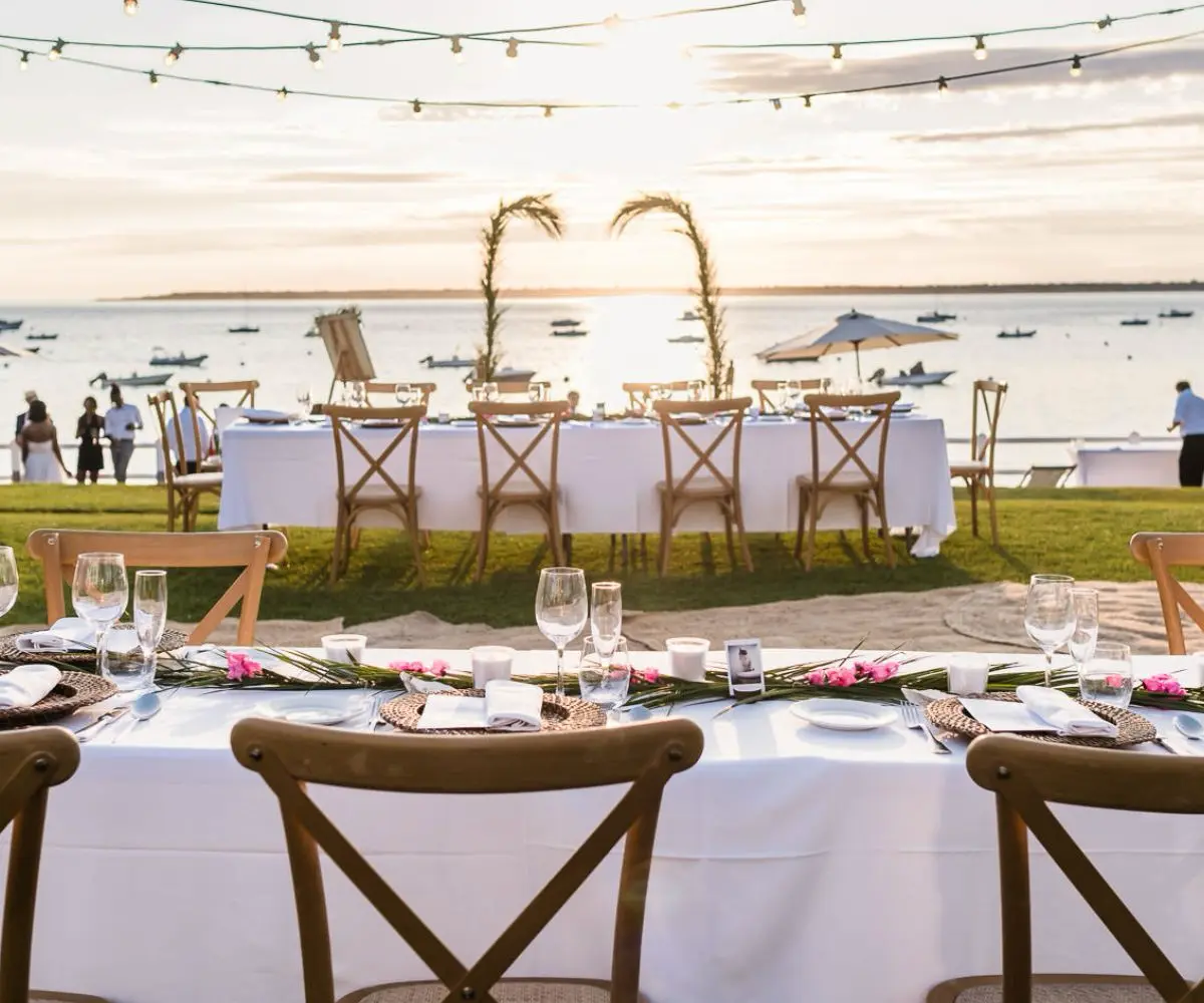 Tables de mariage installées sur une pelouse face au bassin d’Arcachon au coucher de soleil, réception élégante dans une villa privée organisée par wedding planner