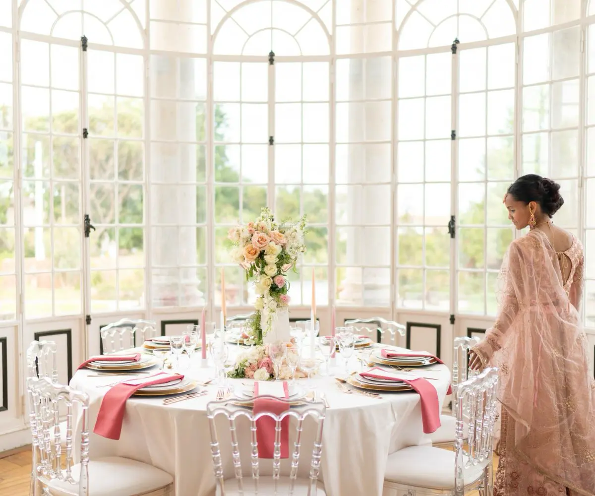 Mariée indienne en sari coloré, révélant avec grâce sa table d’honneur décorée de fleurs et de lumières lors de la réception de mariage.