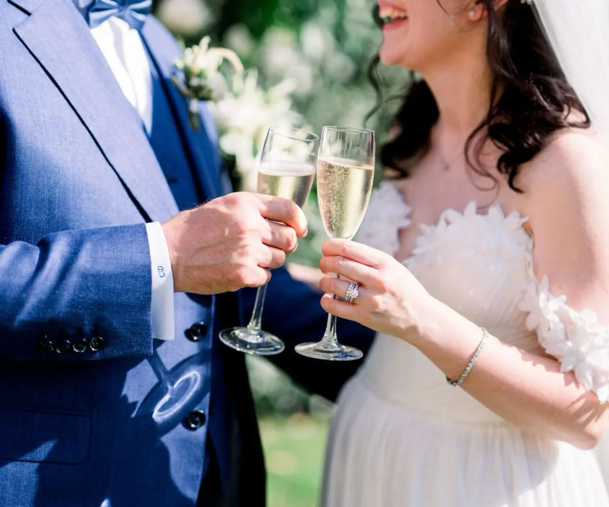Mariés levant leurs verres pour trinquer lors du cocktail de mariage, lançant un moment festif entourés de leurs invités.